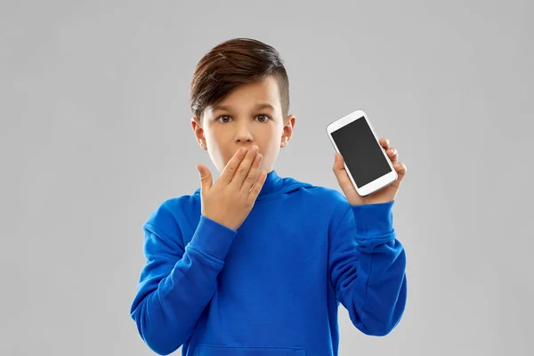 Döbbenten fiú kék kapucnis pulcsit mutatja okostelefon — Stock Fotó