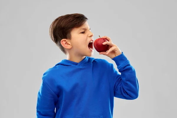 Сердитый мальчик в синей толстовке с красным яблоком — стоковое фото