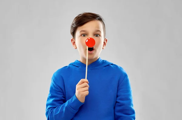 Мальчик в синей толстовке с красным клоунским носом — стоковое фото