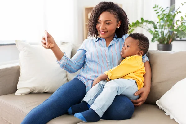 Afrikaanse moeder met baby zoon het nemen van selfie thuis — Stockfoto