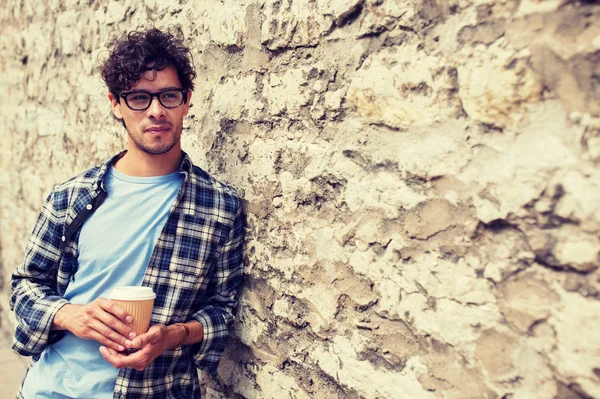 Uomo in occhiali che beve caffè sopra il muro della strada — Foto Stock