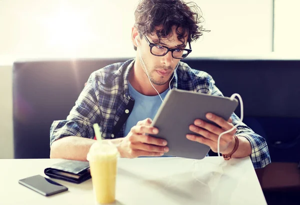 Człowiek z komputera typu tablet i słuchawki, siedząc w kawiarni — Zdjęcie stockowe