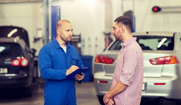 Automechaniker mit Klemmbrett und Mann im Autohaus — Stockfoto