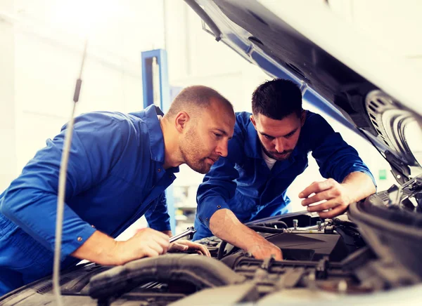 Hombres mecánicos con llave inglesa reparación de coches en el taller — Foto de Stock