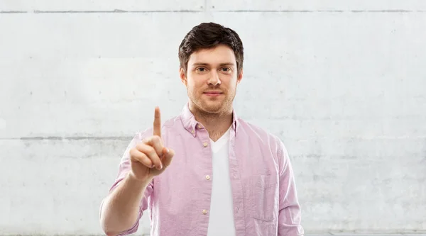 Ung man visar ett finger över grå bakgrund — Stockfoto