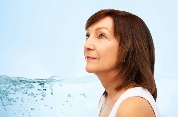 Portrait of senior woman over blue water — Stock Photo, Image