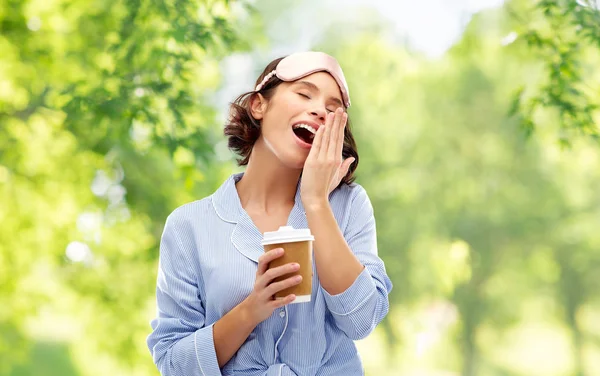 Woman in pajama and eye mask with coffee yawning — Stock Photo, Image