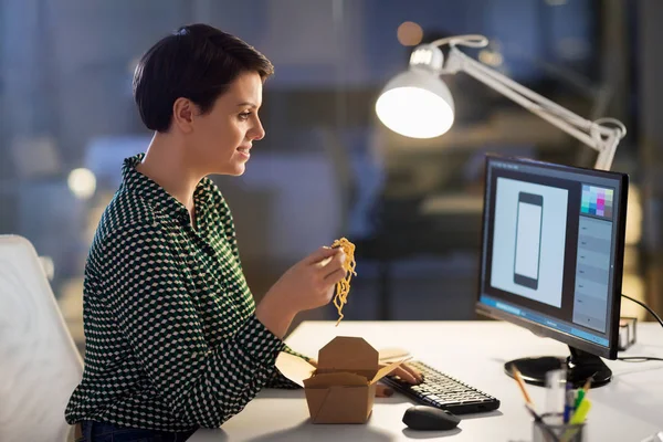 Designer feminino comer e trabalhar no escritório da noite — Fotografia de Stock