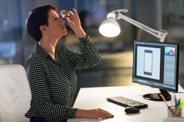 Designerin verwendet Augentropfen im Nachtbüro — Stockfoto