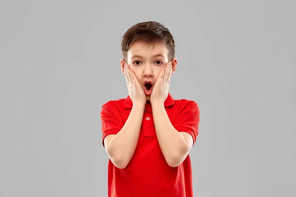 Petit garçon choqué en t-shirt rouge touchant le visage — Photo