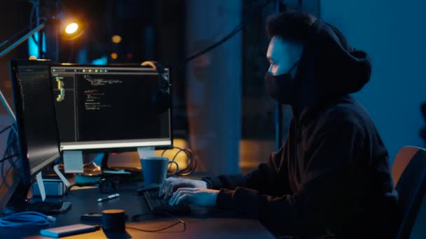 Хакер в маске с помощью компьютеров для кибератаки — стоковое видео