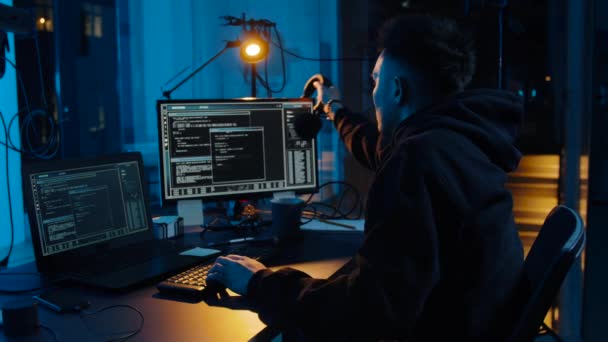 Хакер в наушниках с помощью ноутбука ночью — стоковое видео