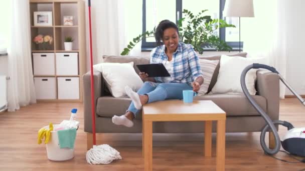 Женщина с планшетным ПК отдыхает после уборки дома — стоковое видео
