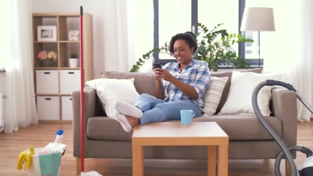 Woman with smartphone resting after home cleaning — Stock Video