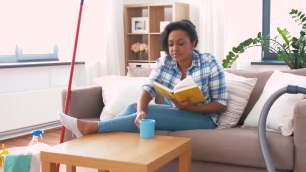Kobieta czyta książkę i odpoczywa po sprzątaniu domu — Wideo stockowe