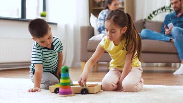 Broer en zus spelen met speelgoed blokken thuis — Stockvideo