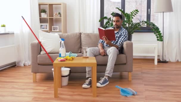 Hombre leyendo libro y descansando después de la limpieza del hogar — Vídeos de Stock