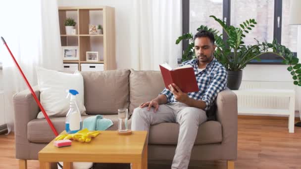 Man reading book and resting after home cleaning — Stock Video