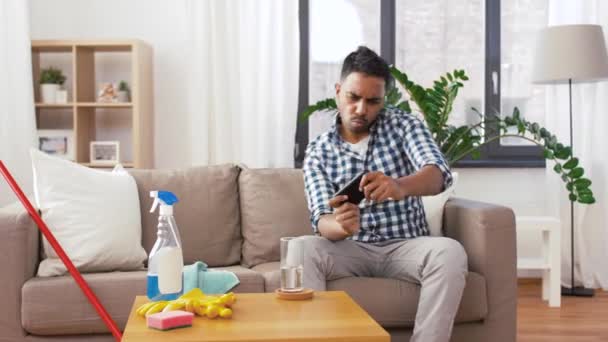 Człowiek gra na smartfonie po sprzątaniu domu — Wideo stockowe