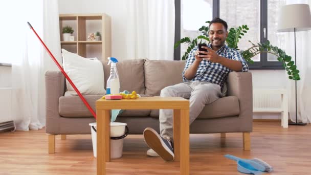 Indio hombre usando smartphone después de la limpieza de casa — Vídeos de Stock