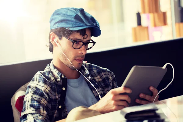 Man met tablet pc en de koptelefoon zit op café — Stockfoto