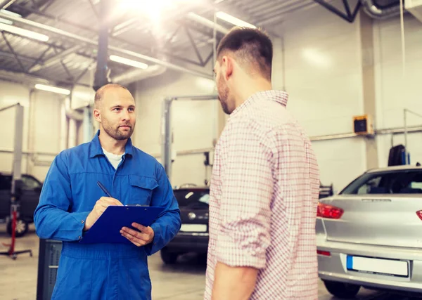 Automechaniker mit Klemmbrett und Mann im Autohaus — Stockfoto