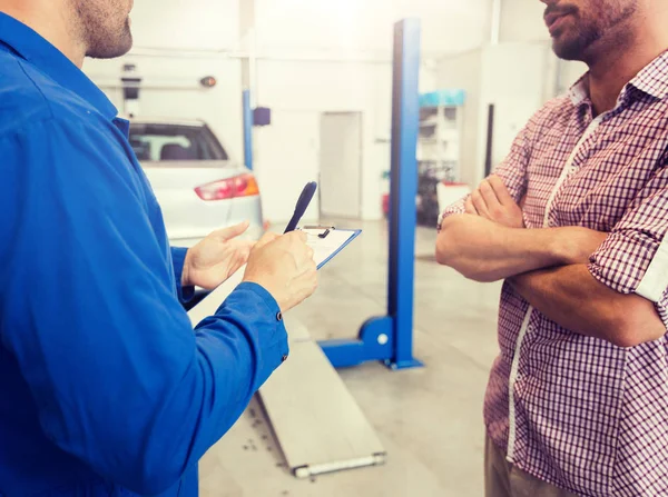 Mecánico de automóviles con portapapeles y el hombre en la tienda de automóviles — Foto de Stock