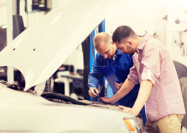 Auto monteur met klembord en man bij de auto-shop — Stockfoto