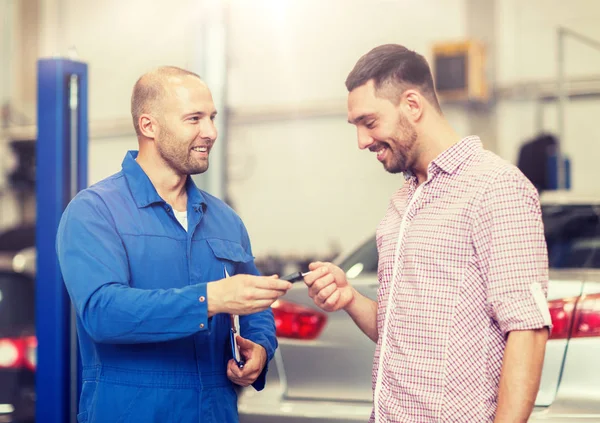 Bilmekaniker som ger nyckeln till mannen på bil shop — Stockfoto