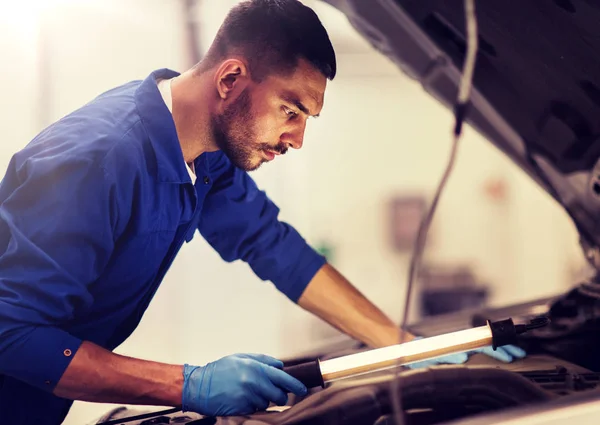 Mecánico hombre con lámpara de reparación de coches en el taller — Foto de Stock