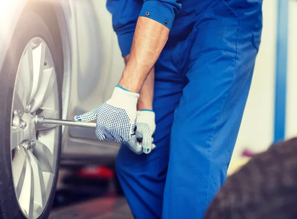 Mecânico com chave de fenda trocando pneu do carro — Fotografia de Stock