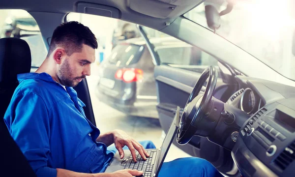 Механічний чоловік з ноутбуком робить діагностику автомобіля — стокове фото