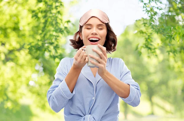 Vrouw in pyjama en slapende masker drinken koffie — Stockfoto