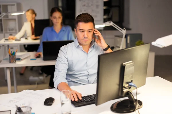 Man ringer på smartphone på natt kontor — Stockfoto