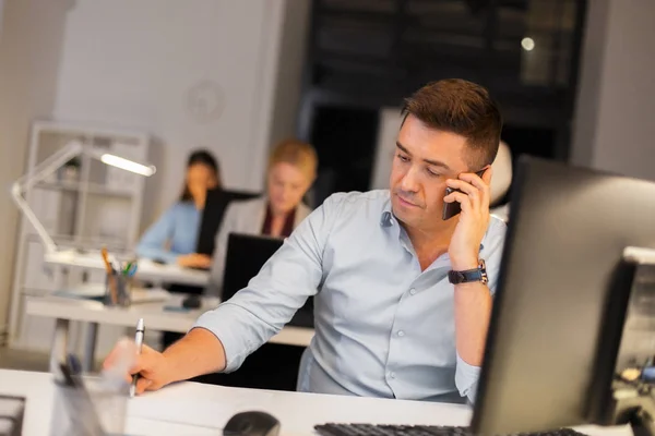 Homem chamando no smartphone no escritório da noite — Fotografia de Stock