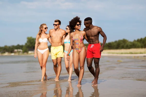 Gemengd ras paar wandelen langs het strand met vrienden — Stockfoto