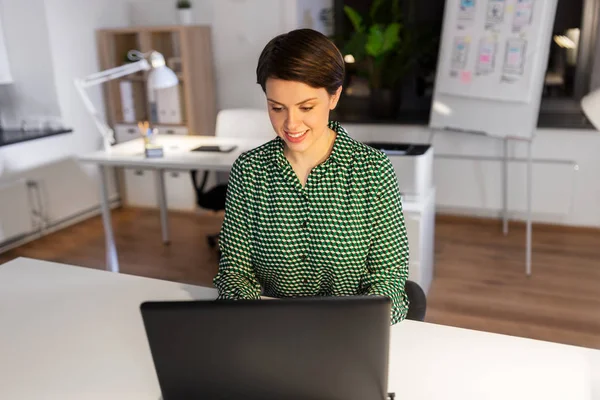 Business woman working on laptop at night office — стоковое фото