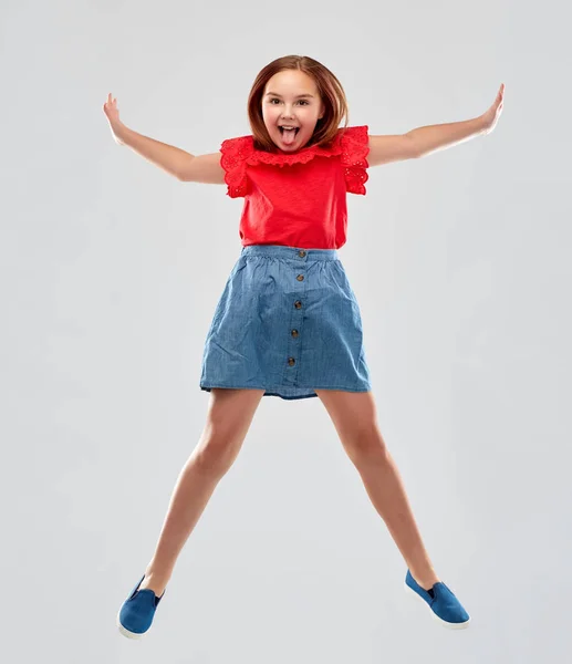 Gelukkig glimlachend meisje in rood shirt en rok springen — Stockfoto