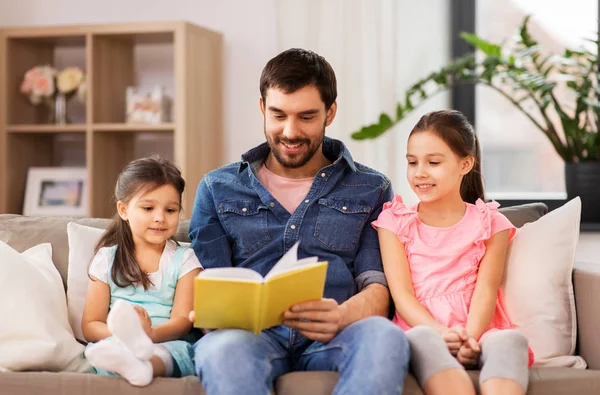 Glücklicher Vater mit Töchtern, die zu Hause Buch lesen — Stockfoto