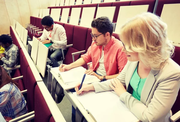 Grupo de estudiantes con cuadernos en la sala de conferencias — Foto de Stock