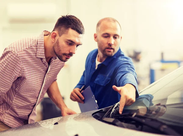 Automechaniker mit Klemmbrett und Mann im Autohaus — Stockfoto