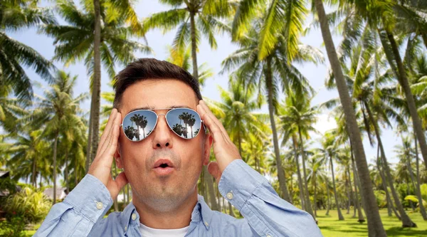 Overrasket mann i solbriller over tropisk strand – stockfoto