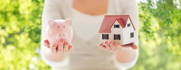 Close up van vrouw met huis model en piggy bank — Stockfoto