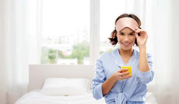 Kvinna i pyjamas och sovmask med juice — Stockfoto