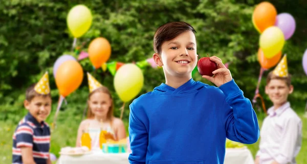 Leende pojke med rött äpple på födelsedagsfest — Stockfoto