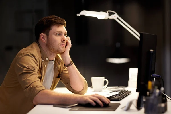 Втомлений або нудний чоловік працює пізно в нічному офісі — стокове фото
