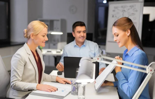 Business-team med papper som arbetar sent på kontoret — Stockfoto