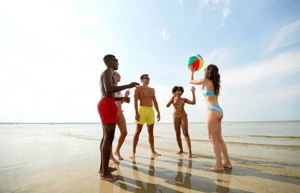 Happy přátelé hrát míč v létě beach — Stock fotografie