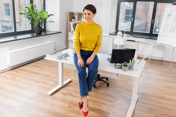 Mulher de negócios feliz sentado na mesa no escritório — Fotografia de Stock