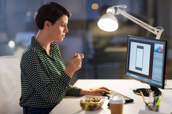 Designer comer e trabalhar no escritório da noite — Fotografia de Stock
